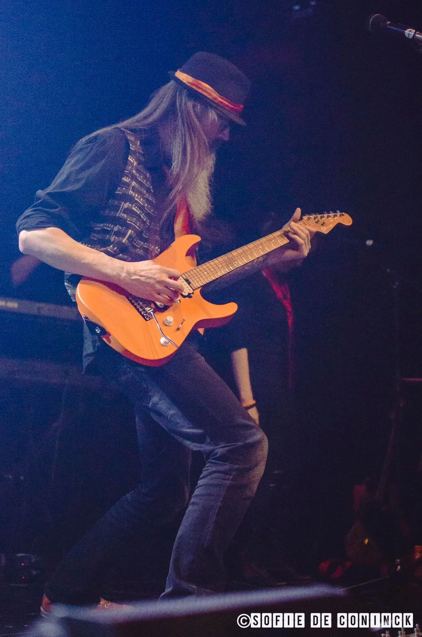 Guitarist with an orange guitar on a blue-lit stage