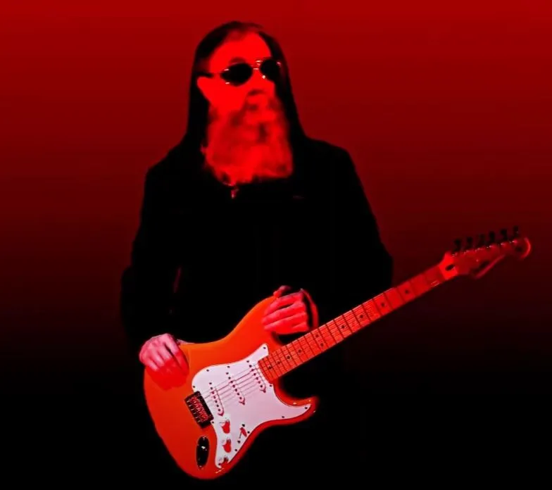 Peter Capon in sunglasses with a red guitar against a red background