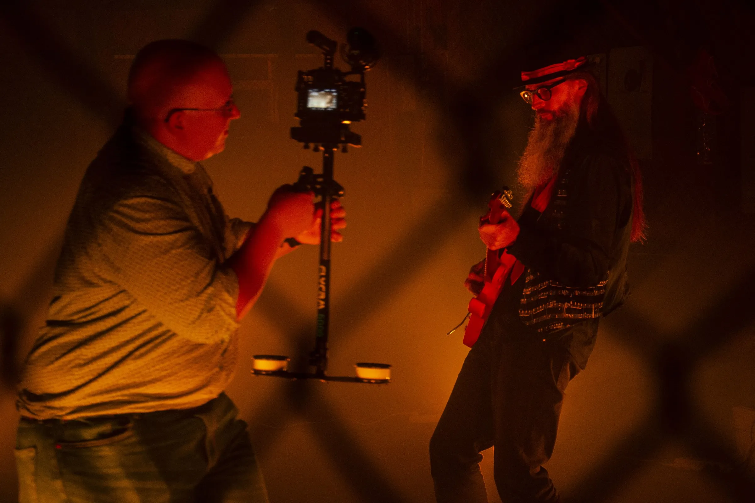 Camera operator filming a guitarist in red light